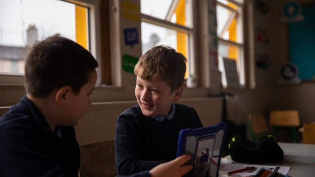 This is a photo of two boys in a school using an ipad