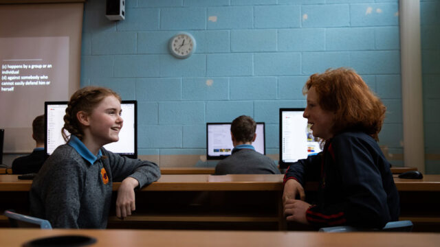 This is a photo of two pupils talking and laughing in a classroom.